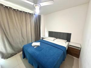 a bedroom with a blue bed with two towels on it at Prainha - Apartamento 3 Quartos in Arraial do Cabo +41 photos