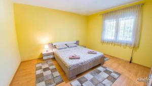 a bedroom with yellow walls and a bed with two pink pillows at Villa Amor in Mostar