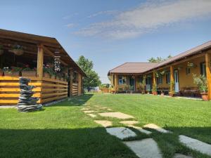 a house with a grass yard next to a building at Casa Adrian in Corbu