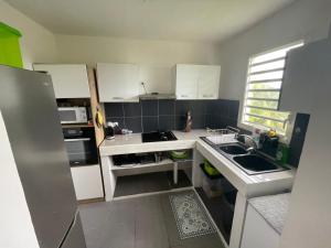 a small kitchen with white cabinets and a sink at colibris Location SAINTE-ANNE in Sainte-Anne +10 photos