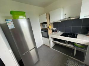 a small kitchen with a stainless steel refrigerator at colibris Location SAINTE-ANNE in Sainte-Anne
