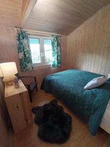 a bedroom with a bed and a table with a lamp at Domki Bieszczadzki Czar Rodzinny 661-850-410 in Polańczyk