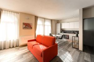 a living room with an orange couch and a kitchen at Residenza Cavour - Appartamento A in Tirano