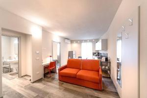 a living room with an orange chair and a kitchen at Residenza Cavour - Appartamento B in Tirano