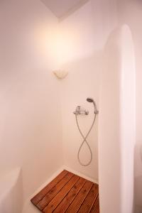 a shower in a white bathroom with a wooden floor at Mykonos Mint Villa - Sofia in Kalafatis
