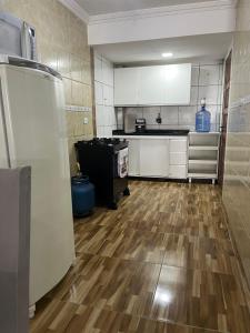 a kitchen with white cabinets and a wooden floor at Casa com Piscina individual in Paulista