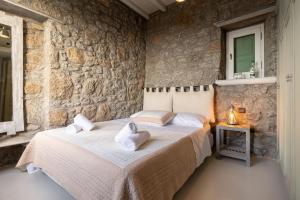 a bedroom with a bed and a stone wall at Mykonos Mint Villa - Sofia in Kalafatis