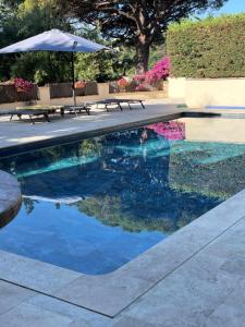 ein Pool mit Bänken und einem Sonnenschirm in der Unterkunft La Beluga in Sainte-Maxime