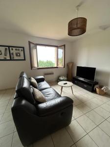 a living room with a black leather couch and a television at Maison avec verger in Azerat
