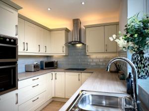 a kitchen with white cabinets and a sink at Keswick Hot Tub Family House in Lytham St Annes