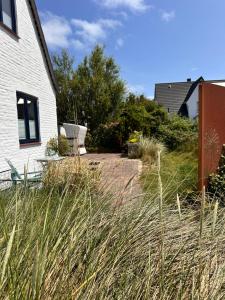 a yard with tall grass next to a house at Dünennest Sylt - Privatgarten mit Leuchtturmblick im Herzen von Hörnum in Hörnum