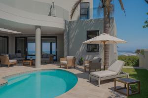 a villa with a swimming pool with chairs and an umbrella at Haven Hill in Knysna