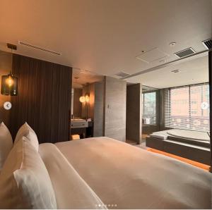 a bedroom with a large bed and a bath tub at THE skM TOKYO HOTEL & DINING in Tokyo