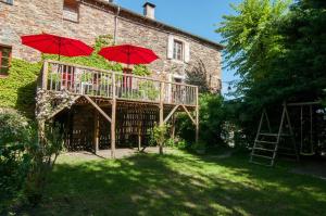 a balcony with red umbrellas in front of a building at Gîte du Grand Sourel, sa vue et son jardin in Moissac-Vallée-Française