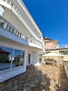 a white house with a patio and an umbrella at Marina Elegance Apartments in Balchik