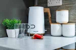 Un mostrador con tazas y otros electrodomésticos encima. en The Heron by Nesting Hub, en Stoke on Trent