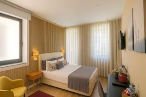 a hotel room with a bed and a yellow chair at MyTrip Porto in Matosinhos