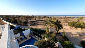 an aerial view of a resort with a pool and palm trees at maison d hôte rêve de désert jerba vue de mer in Al Ḩaddādah