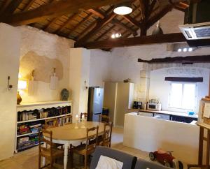 a kitchen and dining room with a table and a refrigerator at Les chambres de la grange in Cherval