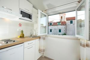 une cuisine avec des placards blancs et une grande fenêtre dans l'établissement Apartments & Room Rollex, à Split