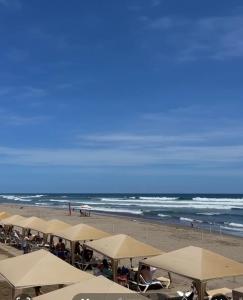 a beach with white umbrellas and the ocean at luxury en Diamante Acapulco para 10 personas in Acapulco