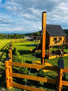 a wooden house in a field with a fence at ORAWSKA CHATA - domek pod Babią Górą in Zubrzyca Górna