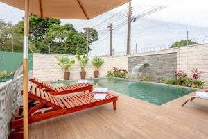 a patio with a pool and two chairs and an umbrella at RESORT PARTICULAR perfeito p/ famílias com crianças e grupos in Foz do Iguaçu
