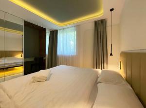 a bedroom with a large white bed and a mirror at NUC living - Apartment 01 in Suceava