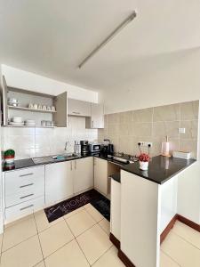 a kitchen with white cabinets and a black counter top at Seville Stays Cozy Getaway in Mombasa +2 photos