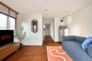 a living room with a blue couch and a tv at Emily Home-Charming 3BR in Chiang Mai Old Town, Steps from Wat Phra Singh & Sunday Walking Street by Beginning With in Chiang Mai