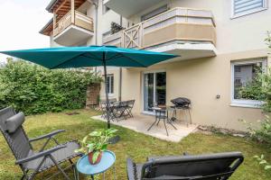 a patio with a table and a blue umbrella at Un havre de paix in Thonon-les-Bains