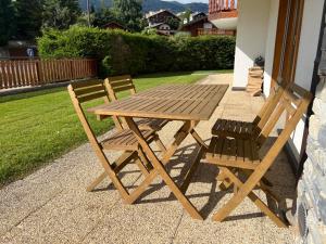 a wooden picnic table and two chairs sitting next to a house at Apartment with a garden, close to golf in Lens