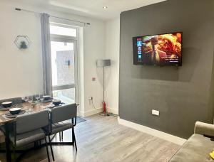 un salon avec une table et une télévision murale dans l'établissement Emerald Living, 4 bedrooms, sleeps 6, free parking in the heart of Swansea!, à Swansea