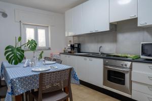 马泰拉La Lanterna Del Sasso的厨房配有白色橱柜和带蓝色桌布的桌子。