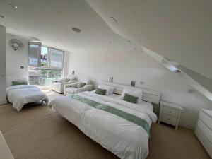 a white bedroom with two beds and a couch at 4 to 5 Bedroom beautiful holiday home London sleeps 9-central Links in London