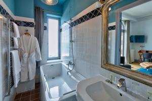 a bathroom with a tub and a sink and a mirror at Hotel Le Rayon Vert in Étretat +37 photos
