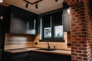 a kitchen with black cabinets and a brick wall at Karma Chic&Style Intera Villa in Korçë