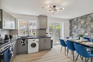 a kitchen with a washing machine and a table with blue chairs at Large 5Bed House London Next CUH Free Parking in Mitcham Junction