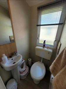 a bathroom with a toilet and a sink and a window at The mistral lido beach Prestatyn in Prestatyn