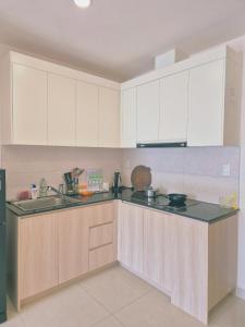 una cucina con mobili bianchi e un piano di lavoro nero di Căn hộ 2 phòng ngủ 2 vệ sinh - Bãi Cháy Hạ Long Dragon Castle a Ha Long