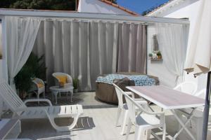 a patio with white chairs and a table and a bed at GITE AVEC SPA ENTRE FORET ET PLAGE - Ambiance Bord de Mer in Saint-Hilaire-de-Riez