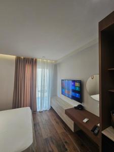 a hotel room with a bed and a flat screen tv at Dejvid's Apartment in Polisi i Vogël