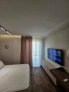 a hotel room with a bed and a flat screen tv at Dejvid's Apartment in Dhërmi
