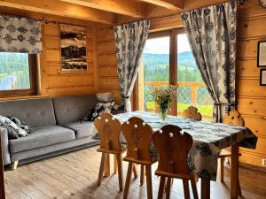 a dining room with a table and chairs and a couch at Witowiańskie Domki z prywatnym jacuzzi i kominkiem in Dzianisz