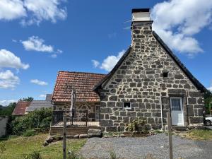 an old stone building with a roof at La maison des petites choses, la tiny house du Puy Mary-Cantal in Lascelle