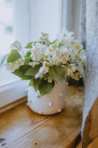 a white vase filled with white flowers on a wooden floor at Old Believers Apartment in Rēzekne +64 photos