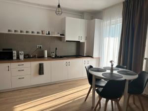 a kitchen with white cabinets and a table and chairs at Family Haven Segesvár in Sighişoara