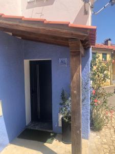 a door to a blue house with a wooden beam at Moradia Vinhais in Vinhais