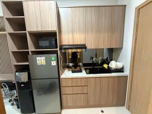 a kitchen with wooden cabinets and a refrigerator at Cozy Studio Near BCS and Grand Batam Mall - with Netflix & free wifi in Nagoya