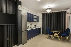 a kitchen with blue cabinets and a table and chairs at Aparthotel C52 - Alezzi Odyssey Pool & Spa Resort in Mamaia Nord